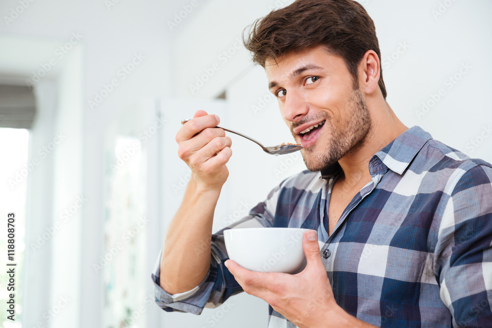 Man eating cereals with milk for breakfast on the kitchen Man eating cereals with milk for breakfast on the kitchen