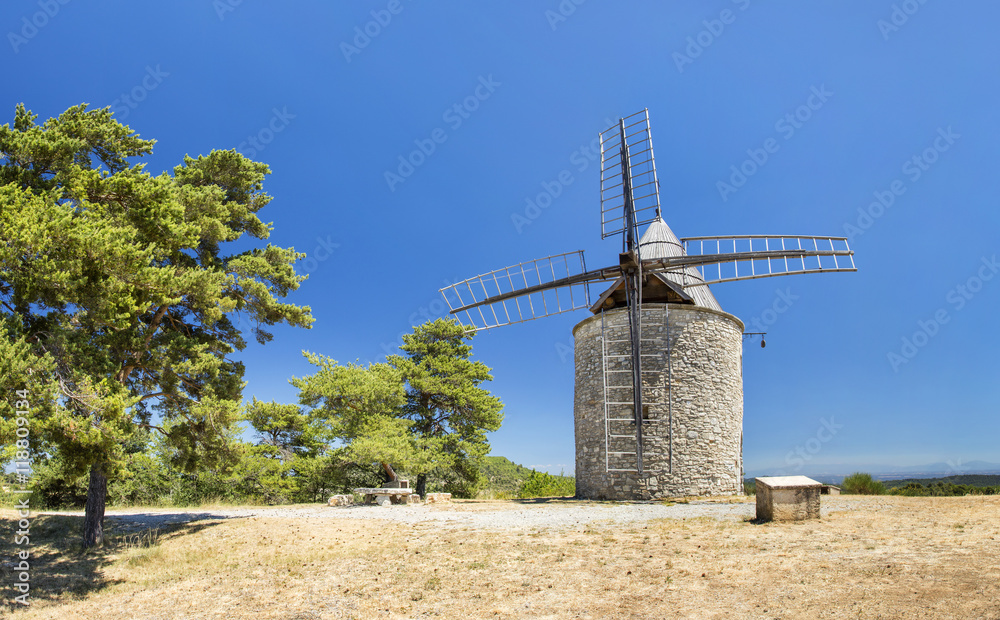 trees and old mill under blue sky in France