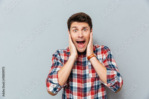Tableau sur toile Astonished shocked young man in checkered shirt standing and shouting