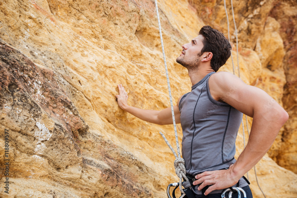 Fototapeta premium Young handsome sportsman getting ready to climb a cliff