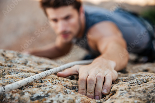Fotografie, Obraz Man reaching for a grip while he rock climbs
