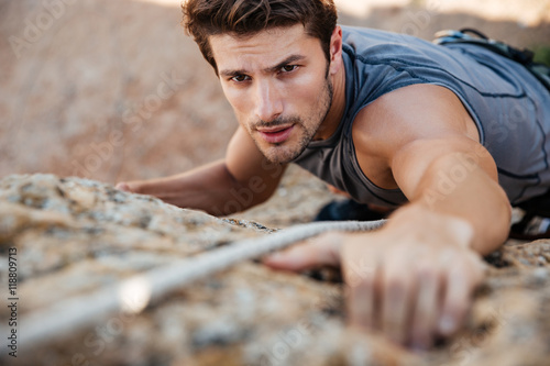 Man reaching for a grip while he rock climbs