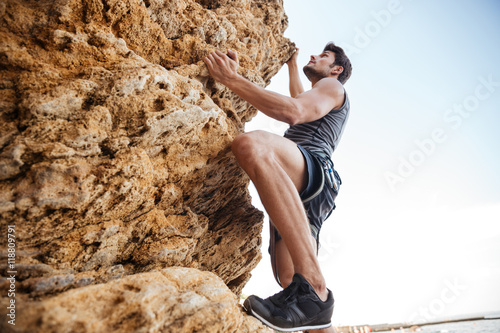 Young man climbing natural rocky wall