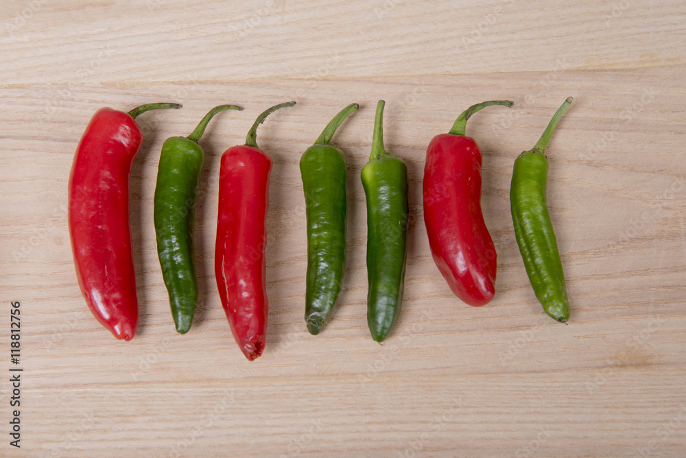 A line of red and green chilli peppers on a wooden background 