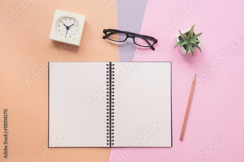 Top view of notebook with pen, eyeglasses, clock, plant on paste