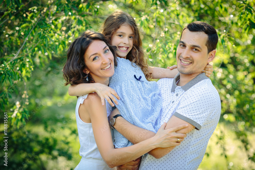 Young happy family three daughter mother and father hug each other in the park Young happy family three daughter mother and father hug each other in the park