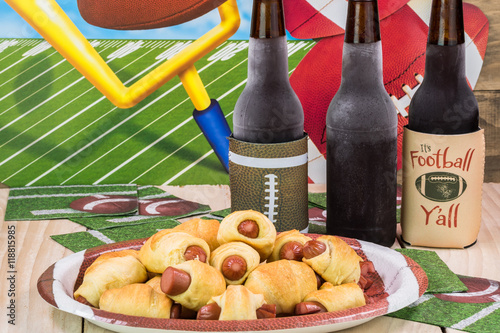 Bottles of cold beer and plate with pigs in blanket on the table