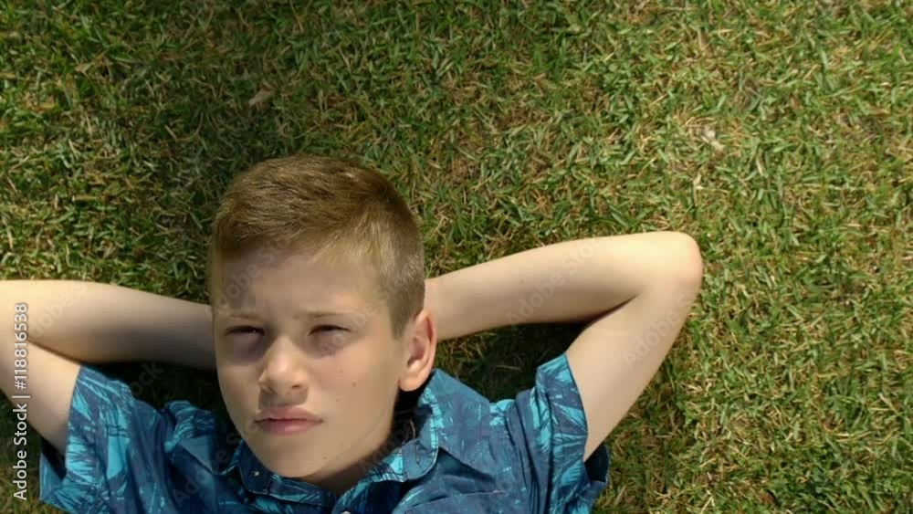Portrait of a teenage boy lying in the grass. Child relaxing in a field in spring, summer. Portrait of a teenage boy lying in the grass. Child relaxing in a field in spring, summer.