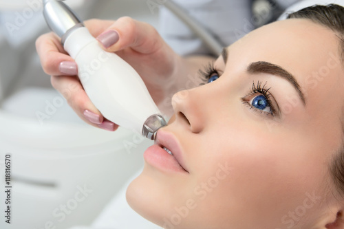 Therapist beautician makes a rejuvenating facial massage for the  woman photo