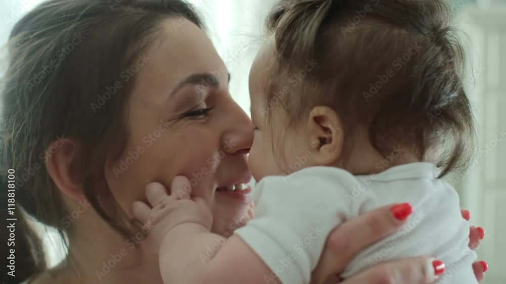 Joyful mother holding her little baby with pacifier in her mouth and rubbing noses with her Joyful mother holding her little baby with pacifier in her mouth and rubbing noses with her