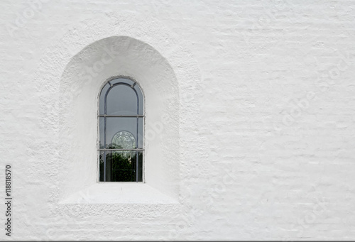 Arched latticed window in a white church wall