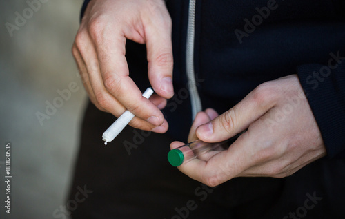 close up of addict hands with marijuana joint tube
