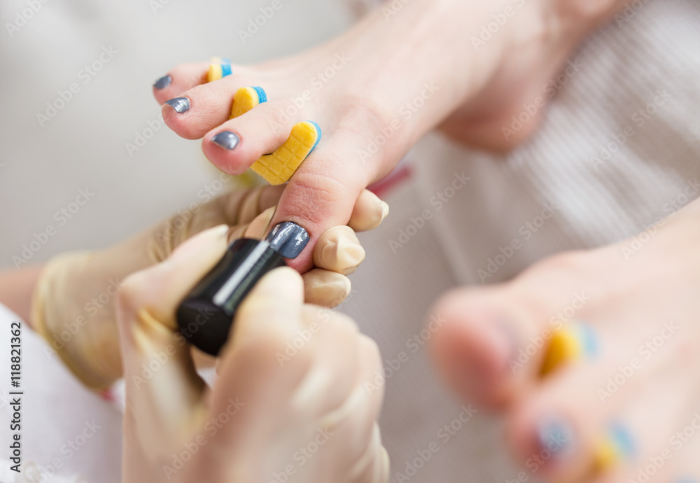 Pedicurist applying nail polish, close up photo Pedicurist applying nail polish, close up photo