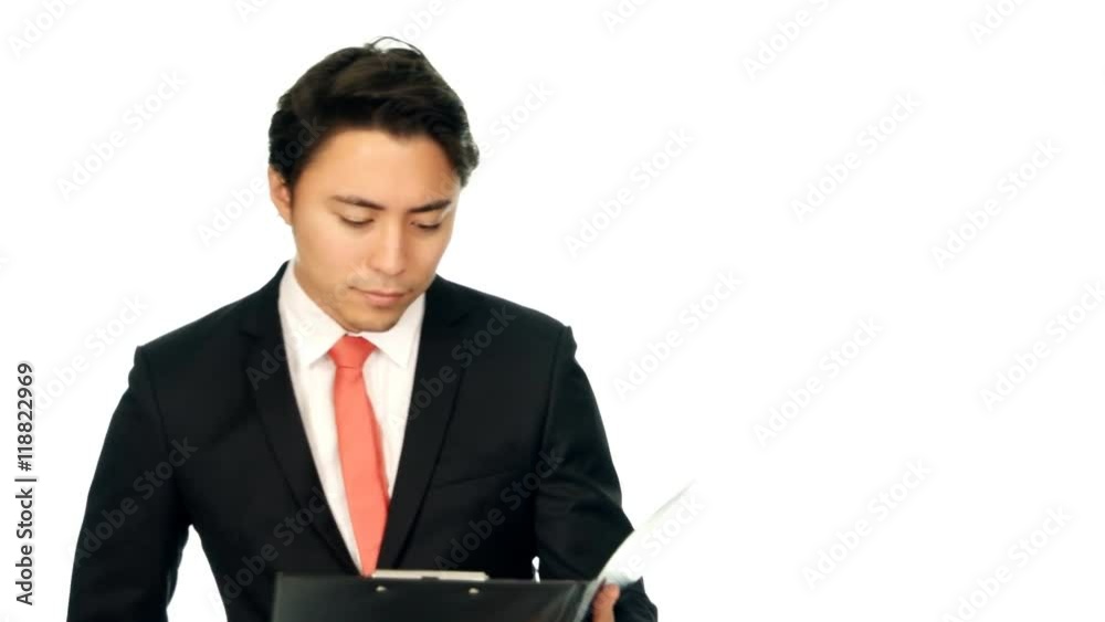 An attractive businessman in a black suit and red tie, walking in front of camera holding a clipboard. Smiling and looking at camera. White background. An attractive businessman in a black suit and red tie, walking in front of camera holding a clipboard. Smiling and looking at camera. White background.