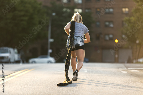 Fitness girl exercising with ropes on the street