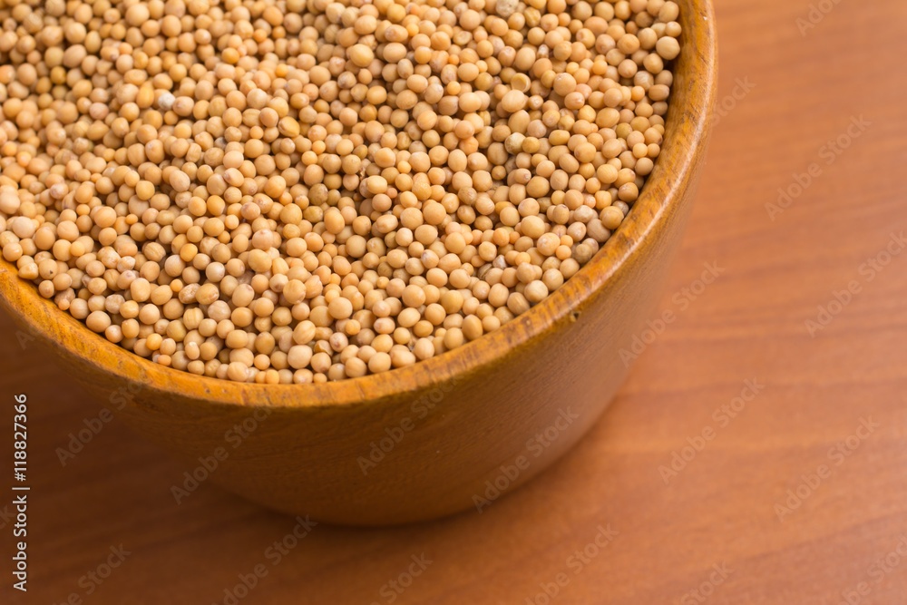 Mustard seeds into a bowl over a wooden table Mustard seeds into a bowl over a wooden table