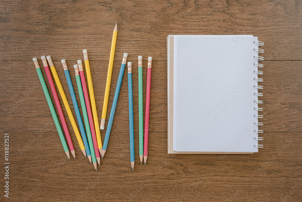 Obraz premium multicolor pencils and blank notebook on wooden background