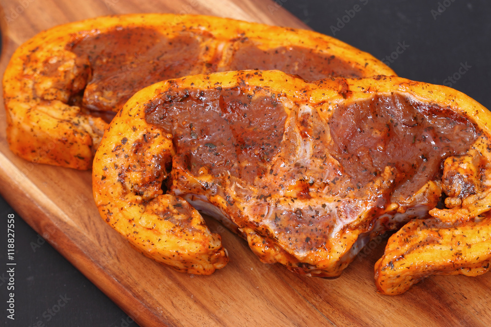 Raw lamb chops with a mint sauce marinade on a wooden chopping board Raw lamb chops with a mint sauce marinade on a wooden chopping board