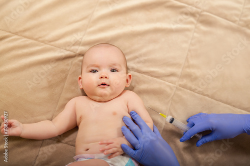 Baby receiving vaccine. Pediatrician giving a baby girl intramuscular injection in arm