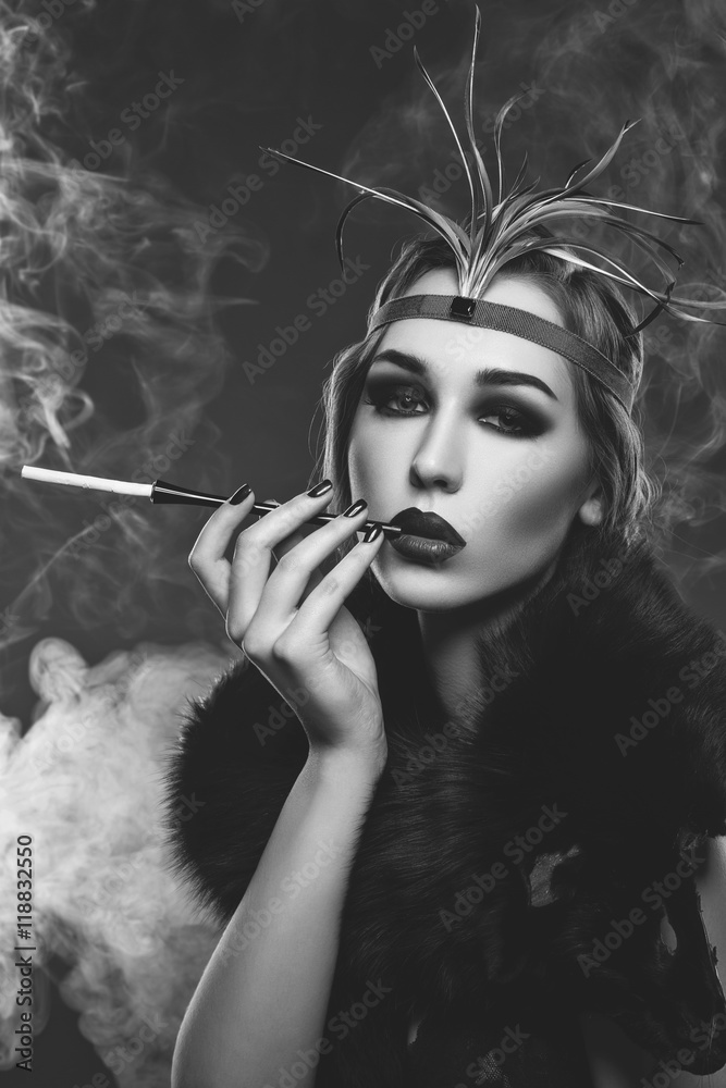 Obraz premium Beautiful girl with smoky eyes and red lips holding cigarette