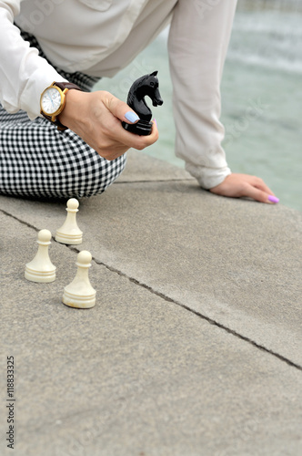 Woman holds chess knight in her hand.