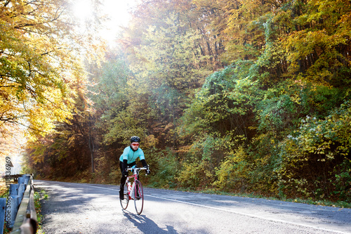 Young sportsman riding his bicycle outside in sunny autumn natur