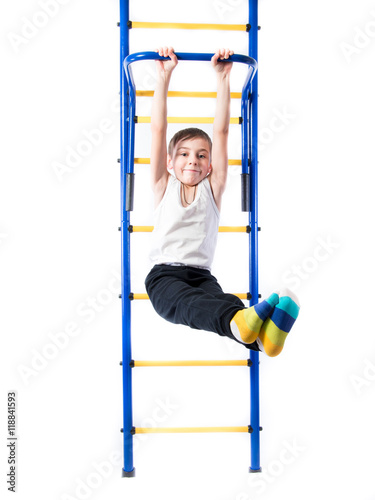 Little boy on the bar whist legs outstretched and smiling on a white background