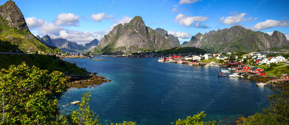 Obraz premium Reine in Lofoten Islands, Norway, with traditional red rorbu huts under blue sky with clouds.