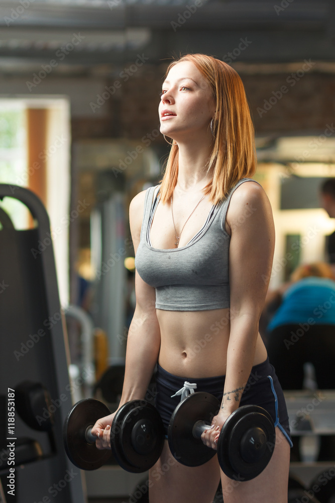 Fototapeta premium Concept: sport, healthy lifestyle. Young strong girl do exercises with dumbbells