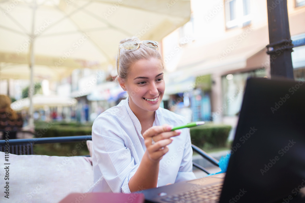 Fototapeta premium Beautiful business young woman sitting in cafeteria and working on laptop.