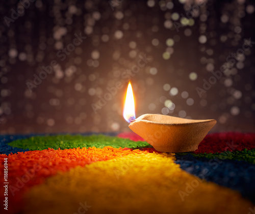 Traditional diya lamp lit on colorful rangoli