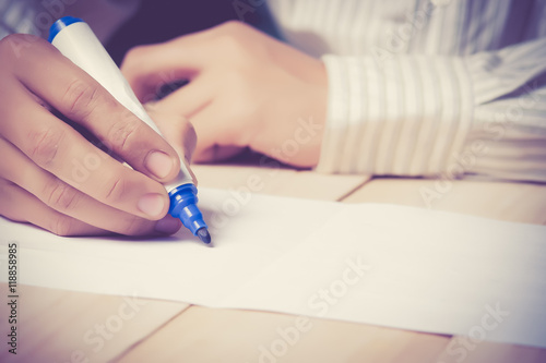 Close-up of Human Hand holding pen Signing on Formal Paper at the Table