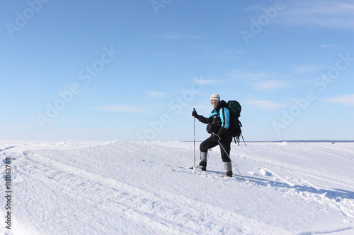 The man the traveler with a backpack skiing on snow of the frozen river 