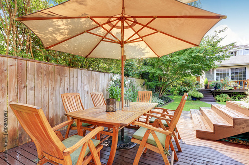 House exterior. Wooden patio table set with umbrella © Iriana Shiyan