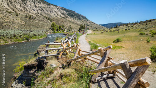 The path with wooden fencing along the creek among the bushes. Fast flowing river on the background of the rocky coast. Boiling River Trail, Yellowstone National Park, Wyoming 