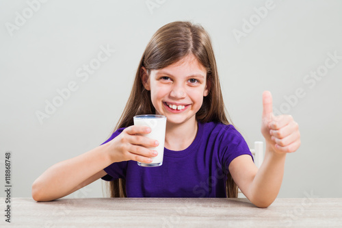 Happy little girl is drinking milk.