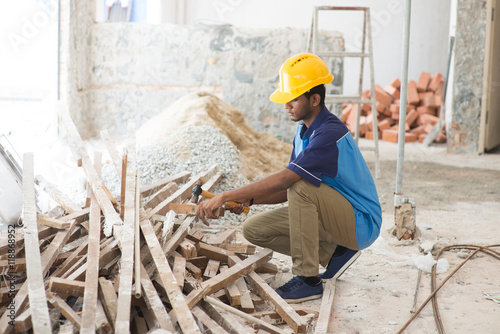 indian male contractor on site using hammer