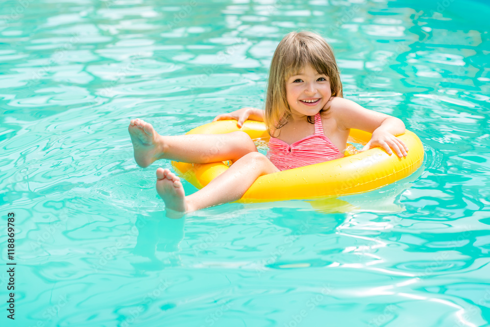 Happy little girl floating in the pool to rescue circle yellow