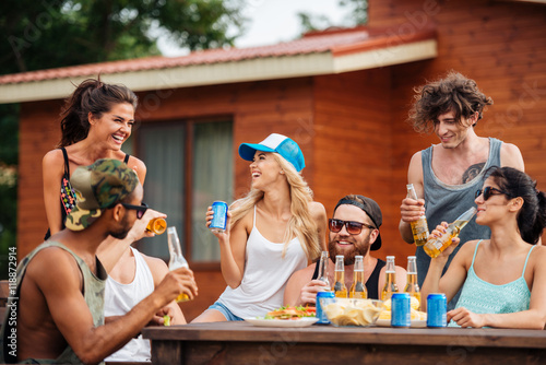 Canvas Print Group of cheerful young people drinking beer and laughing outdoors
