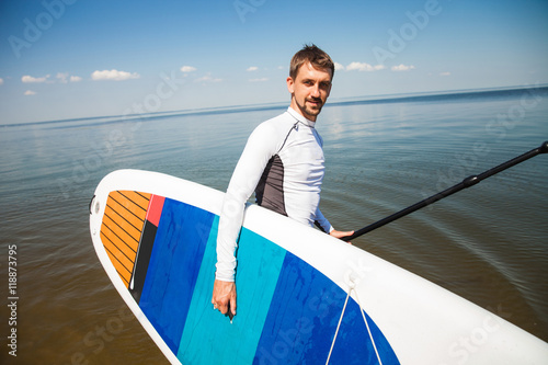 Young man with paddle board on the beach © serhiipanin