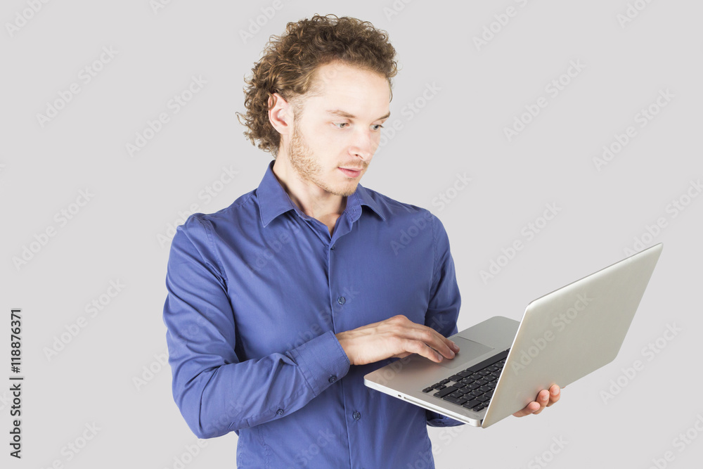 Smart man typing something on laptop in studio on gray background. Modern lifestyle. Smart man typing something on laptop in studio on gray background. Modern lifestyle.