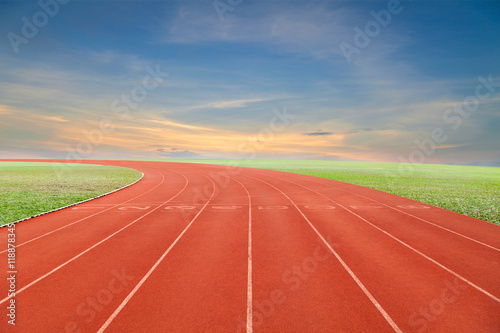  Running track with green grass and blue sky white cloud backgro