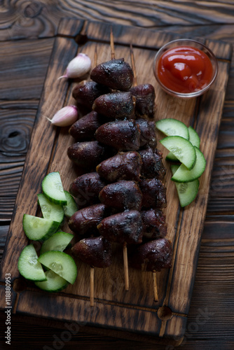 Kabobs with turkey hearts on a wooden serving board, studio shot