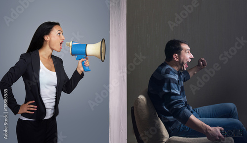 Foto Man watching TV while angry woman calling him through a megaphone