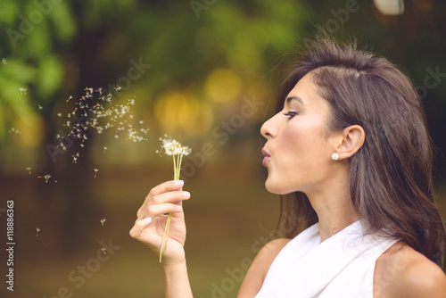 Girl blowing on dandelion in park