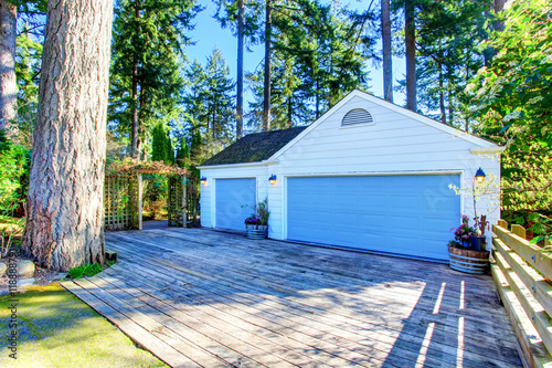 фотографія Separate garage with blue door and wooden driveway.