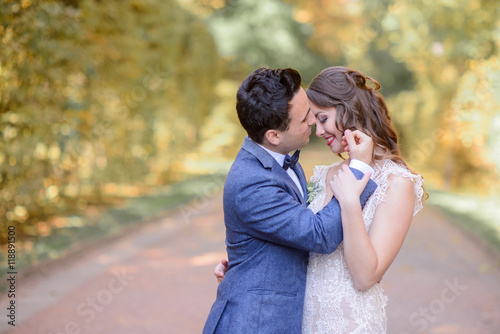 Handsome brunette groom touches bride's face while they pose in