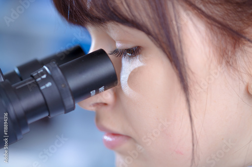 Young woman technician use microscope in laboratory
