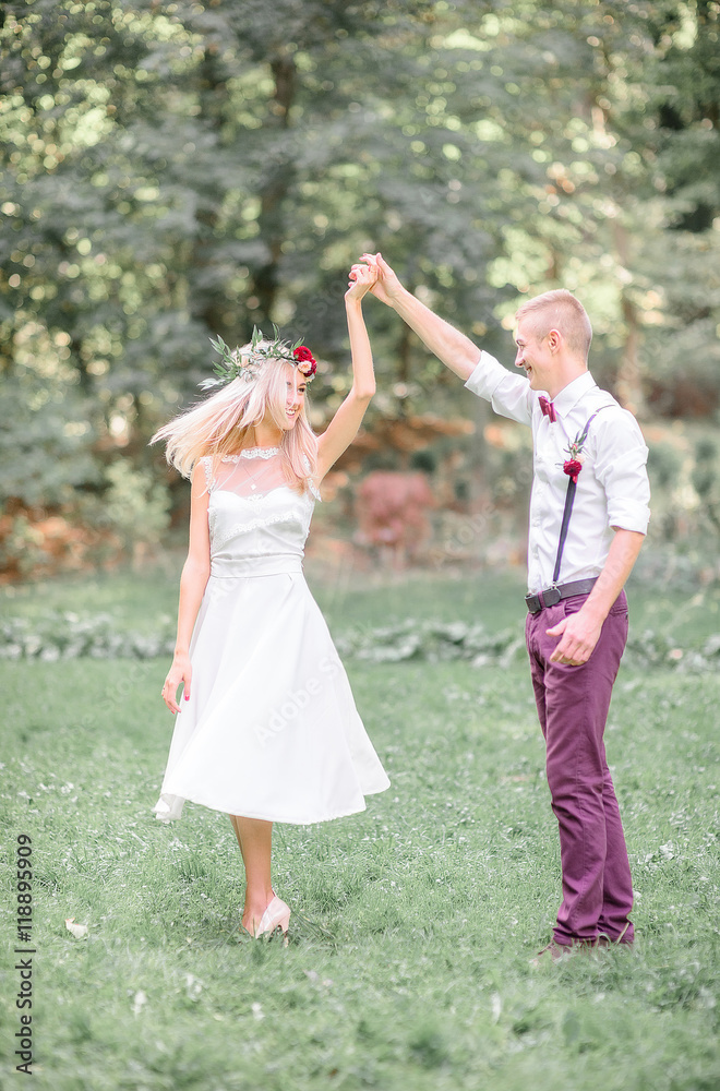 Groom in violet trousers whirls pretty bride in short dress Groom in violet trousers whirls pretty bride in short dress