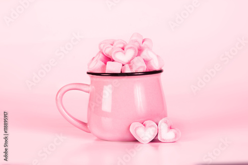 marshmallow heart shape in cup on pink background 